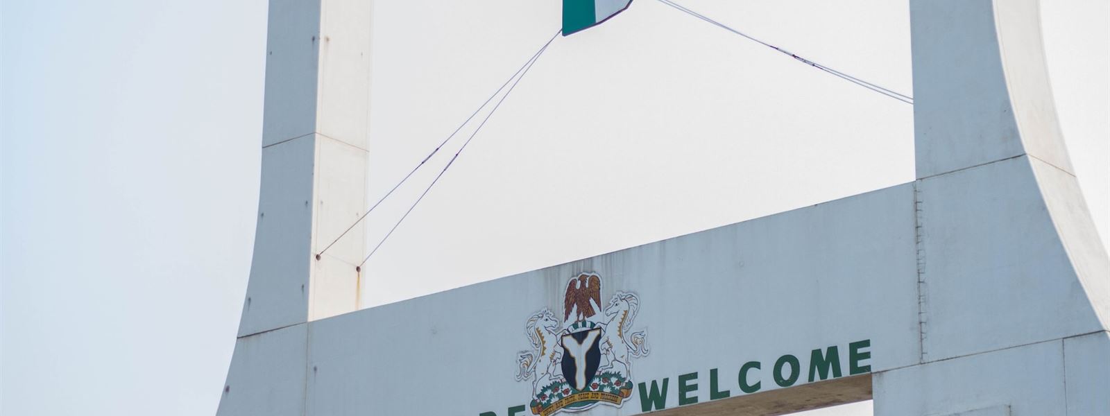 The City Gate in Abuja with the Nigerian flag and the words “You are welcome”